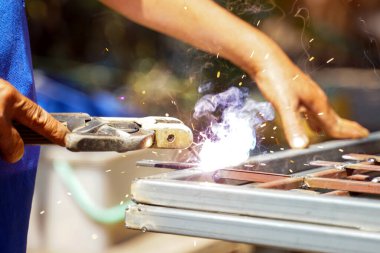 Elektrikli kaynak makinesinin çenesi çelik pencere işçiliğini kaynaklamak için çelik parmaklıkları tutar.                               