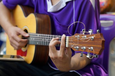 Asyalı çocuk tatilde dışarıda kamp arkadaşlarıyla gitar çalarak mutlu bir şekilde oturur. Yumuşak ve seçici odak.                                 