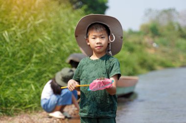 Genç bir kaşif, elinde tatlı su ekosistemlerini keşfetmek için kullandığı bir balık kepçesiyle bir nehirde duruyor. Açık hava aktiviteleri, keşif, doğa, öğrenme kavramı                               