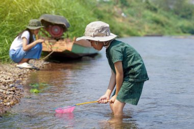 Çocuklar nehrin ekosistemini keşfetmek için balık ağlarını kullanırlar. Açık hava aktiviteleri, keşif, doğa, öğrenme kavramı                               