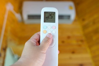 Mobil uzaktan kumanda evdeki klimanın sıcaklığını elektrik tasarrufu için 25 santigrat dereceye ayarlar. Yumuşak ve seçici odak.                                