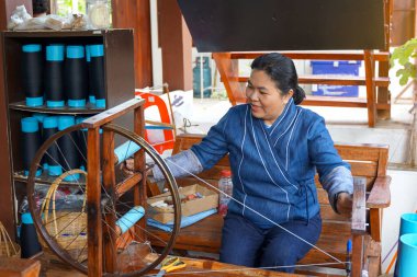 Geleneksel mavi el dokuması kıyafetler giyen Taylandlı kadınlar el yapımı bir makine kullanıyorlar. Halka açık ürünler konsepti için iplik hazırlamak topluluk girişimi El Dokuma                               