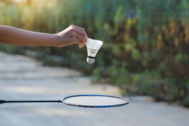 Aşağıdaki badminton raketine salmak için beyaz bir pipi tutan Asyalı kız. Yumuşak ve seçici odak.                               