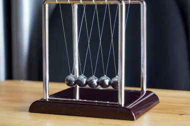 Newton 'un beşiği momentumun korunmasını ve sallanan kürelerle enerjinin korunmasını gösteren bir cihazdır. Yumuşak ve seçici odak.                               