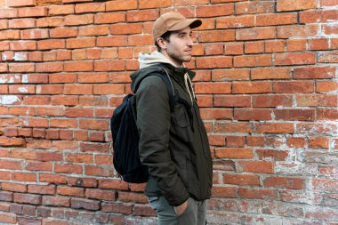 Şehre doğru yürüyen bir adamın yakın çekimi. Tuğla duvar arkaplanı ve kopyalama alanı