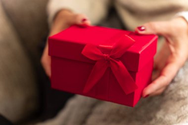 Elleri küçük olan kadın ellerine yakın durun. Kurdeleli kırmızı renkli hediye. Noel hediyesi olarak