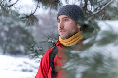 Young handsome caucasian man hiking in the mountain forest during winter season. Sports adventure lifestyle. Trekking in a snowy landscape clipart