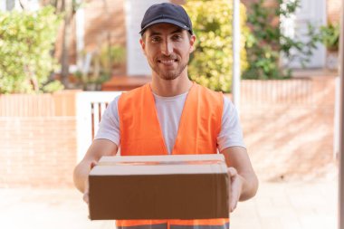 Teslimatçı müşteriye bir paket teslim ediyor. Eller ve karton kutuya yakın çekim