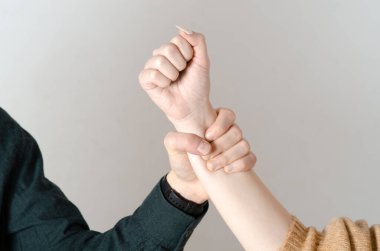 Domestic violence. Man's hand grabbing a woman's arm. Concept of gender violence and mistreatment of women. Background isolated on gray background clipart