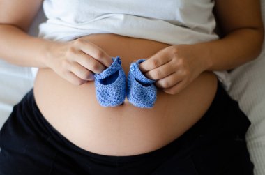 Mavi bebek çoraplı hamile bir anne. Kapatın. Sağlıklı annelik ve hamilelik kavramı