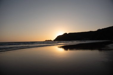 Okyanusta sörf tahtası olan bir sörfçünün altın saati silueti.