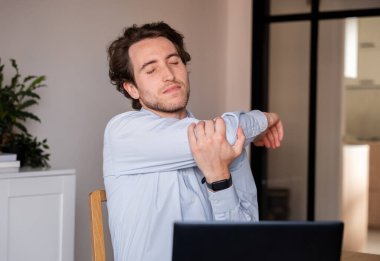 Gerginliği azaltmak için ofiste kollarını açan bir adam.