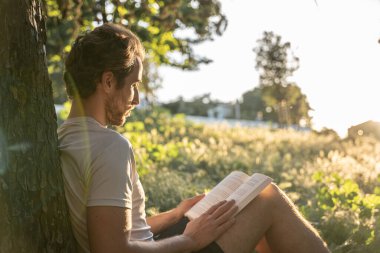 Adam yazın açık havada kitap okumaya odaklanmış.