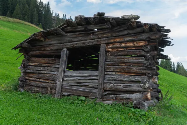 Arkasında dağların olduğu eski ahşap bir ahır. Avusturalya, tirol