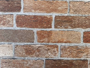 Eski tuğlalardan yapılmış alçısız bir duvarın dokusu düzensiz ateşleme sonucu farklı renkler gösteriyor..