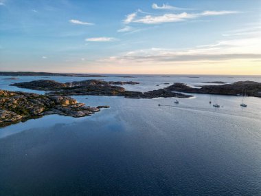 İsveç kıyılarında gün batımında doğal bir limanda tekneler.