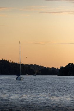 Güneş batarken, bir yelkenli kameraya suyun üstünde yaklaşıyor..