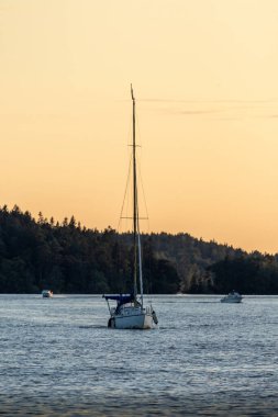 Güneş batarken, bir yelkenli kameraya suyun üstünde yaklaşıyor..