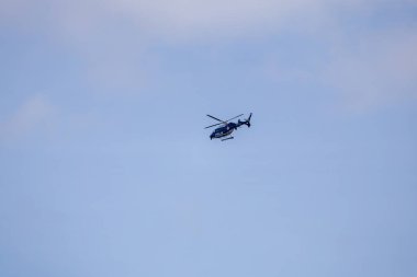 Mavi gökyüzünde uçan bir İsveç polis helikopteri pervanelerini ve parlak tasarımlarını sergiliyor..