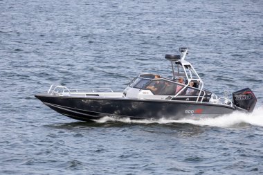 Suyun üzerinde hızla ilerleyen parlak siyah ve gümüş renkli bir motorlu tekne, bir grup insanla birlikte gölde güzel bir gün geçiriyorlar..