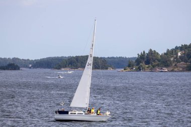Etrafı yemyeşil adalarla çevrili, sakin bir denizde yelken açan iki kişilik bir yelkenli. Gökyüzü birkaç bulutla berrak, sakin bir atmosfer yaratıyor..