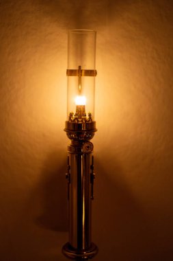 Cam gölgeli klasik bir lamba, yumuşak ve sıcak bir parıltı yayıyor..