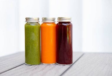 Sağlıklı yaşam tarzı, detoks içecekleri, sağlıklı içecekler, sağlıklı içecek, organik içecek ve yiyecek blogu kullanımı için beyaz arka planda üç renkli soğuk baskılı meyve suyu temiz minimum stok fotoğrafı. İyileşme aşısı.
