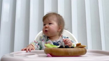 Rengarenk önlüklü sevimli bir kız bebek evde yemek saatinde meyve, sebze ve yumurtalarla sütten kesilmeye başlandı.