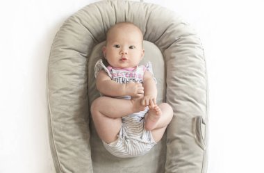 Bebek yuvasında ayaklarıyla oynayan beyaz, şirin bir kız bebek. bebek dönüm noktaları