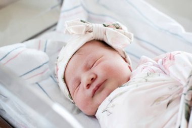 Yeni doğmuş beyaz bir bebeğin portresi hastane kıyafeti içinde. Yeni doğan bebeğin yüzünü kapatın..