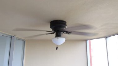 Tavan vantilatörü hızla dönen kahverengi yüzgeçli beyaz fener.