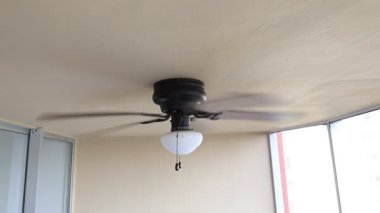 Tavan vantilatörü hızla dönen kahverengi yüzgeçli beyaz fener.