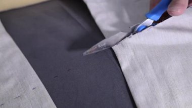 Kumaş kesmek için makas kullanan bir adamın ellerini kapatın.