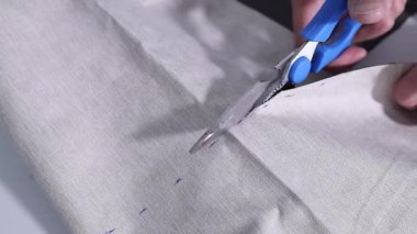 Kumaş kesmek için makas kullanan bir adamın ellerini kapatın.