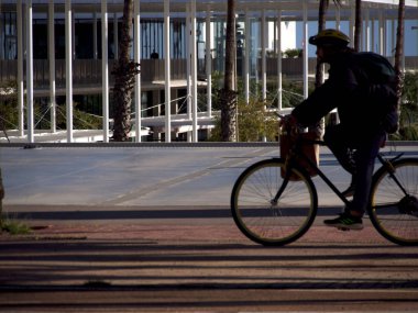 Limanın yanında kaskı olan bir bisikletçinin silueti..