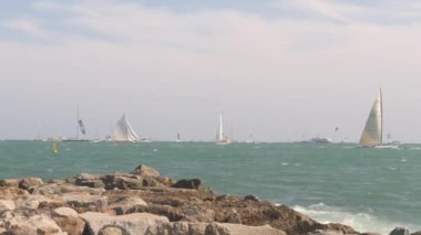 Dalgalar dalgalara çarpıyor yelkenliler geçerken.