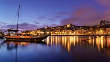 Porto, Portekiz - 26 Nisan 2022: Rabelo teknelerinin mavi saatte Douro Nehri 'ndeki uzun pozlu fotoğrafı.