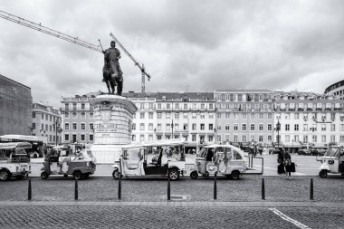 Tuk Tuks and Pedicabs by the Statue of King Joo I. Praca da Figueira, Baixa neighborhood of Lisbon. In Black and White. Lisbon, Portugal - April 21, 2022 clipart