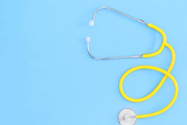 Flat lay yellow stethoscope blue background space for copy.