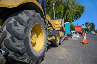 Excavator in the street with portable toilet. Construction in the Rancho Palos Verdes, especially the Portuguese Bend areas. Area affected due to ongoing land movement. clipart