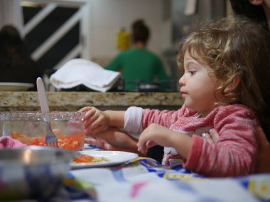 Öğle yemeği vakti çocuk yiyor ve eğleniyor.