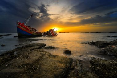 Shipwreck in the midst of submerged rock zone near by the coast. This photo shoot by low speed during the twilight time. clipart