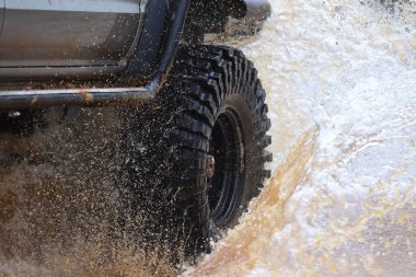 Yüksek katlı 4 * 4 kamyonet bataklıktan geçiyor ve büyük bir su sıçrıyor..