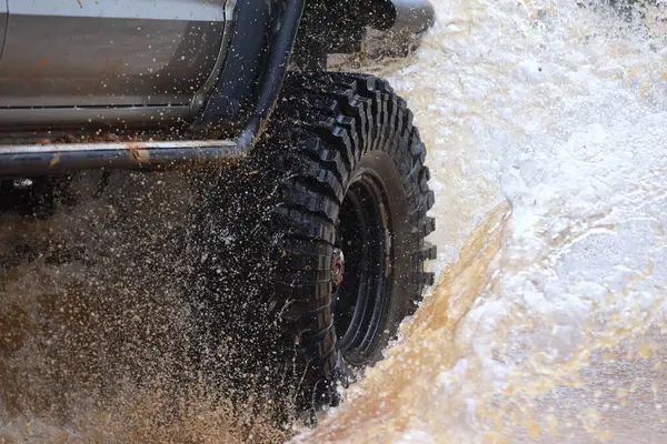 Yüksek katlı 4 * 4 kamyonet bataklıktan geçiyor ve büyük bir su sıçrıyor..