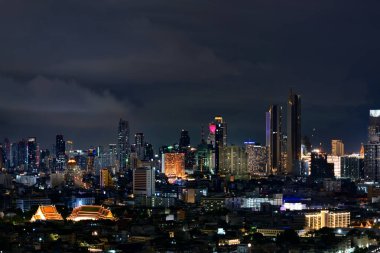 Bir açının şehri olan Bangkok 'taki geleneksel ve modern hayatın uyum kombinasyonu. Arka plandaki gökdelenler arasında geleneksel Tayland tarzı tapınağı gösteren fotoğraf..