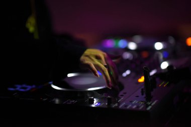 Bir DJ, canlı bir konsolun karıştırıcı pikabını, elektrik eğlenceli bir ses ortamı yaratacak şekilde ayarlar. Gece hayatının titreşimli ritmini yaşamak.