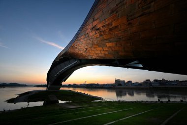 Pasan, the iconic buildings of the beginning of the Chao Phraya River,Thailand. A bridge form building in the twilight shades and its surface  was covered by copper plate that reflected the light. clipart