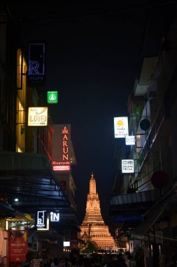 Bangkok, Tayland 16 Kasım 2024: Wat Arun yılbaşı kutlamaları için ışıklandırmasıyla. Ön planda neon ışıklarıyla eski şehir sokağından ateş açıldı..