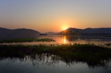 Sabahleyin Man sagar gölünün ve onun su sarayının (Jal Mahal) ihtişamı. Senery göldeki güzel antik sarayı ve etrafta uçuşan kuşu gösteriyor..