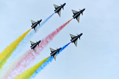 Tayland hava gösterisinde, Cinese akrobatik takımı uçuyor ve kuyruğundan renkli dumanlar salıyor.. 